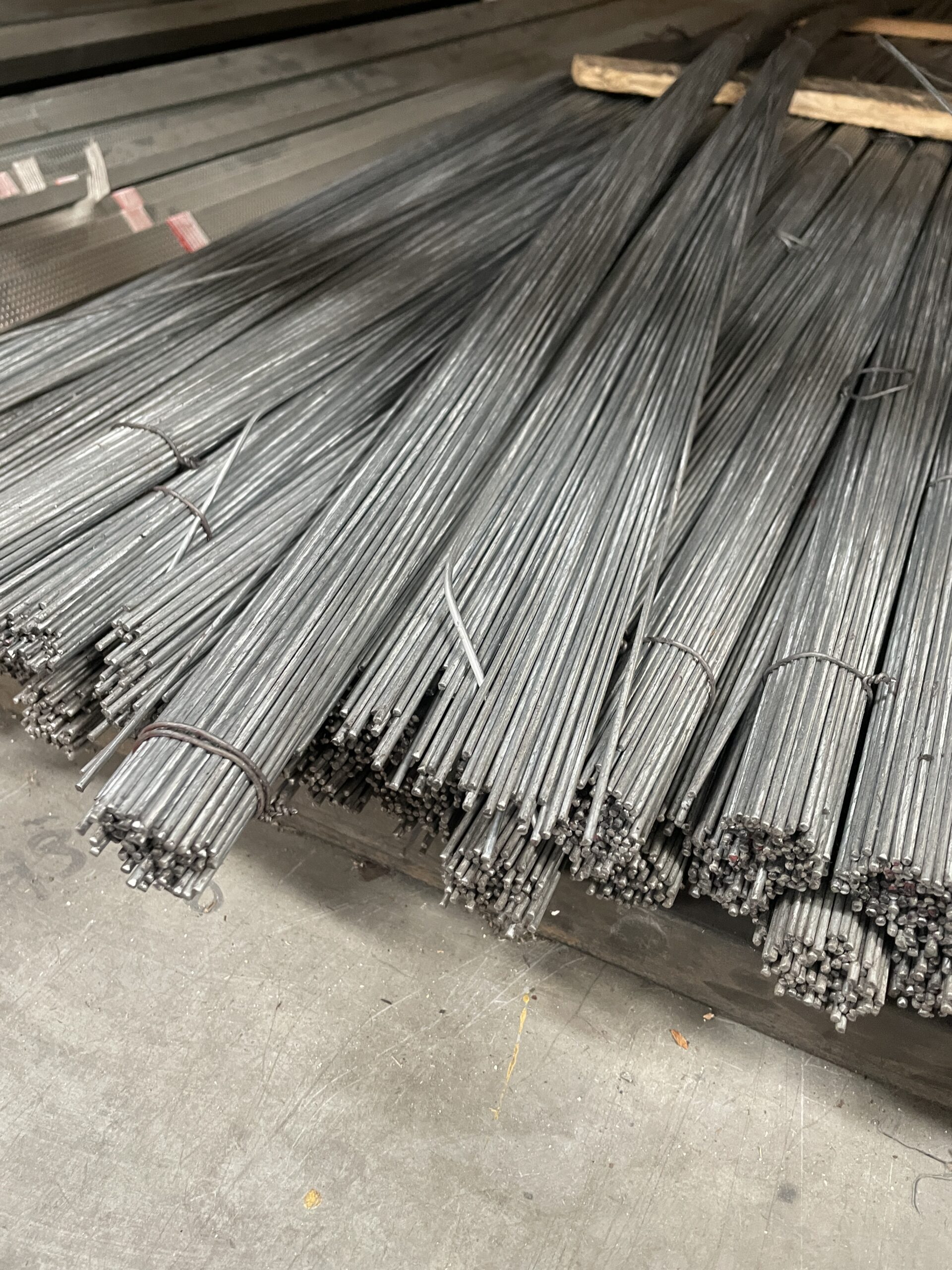 Bundles of straight galvanized hanger wires neatly organized in a warehouse setting.